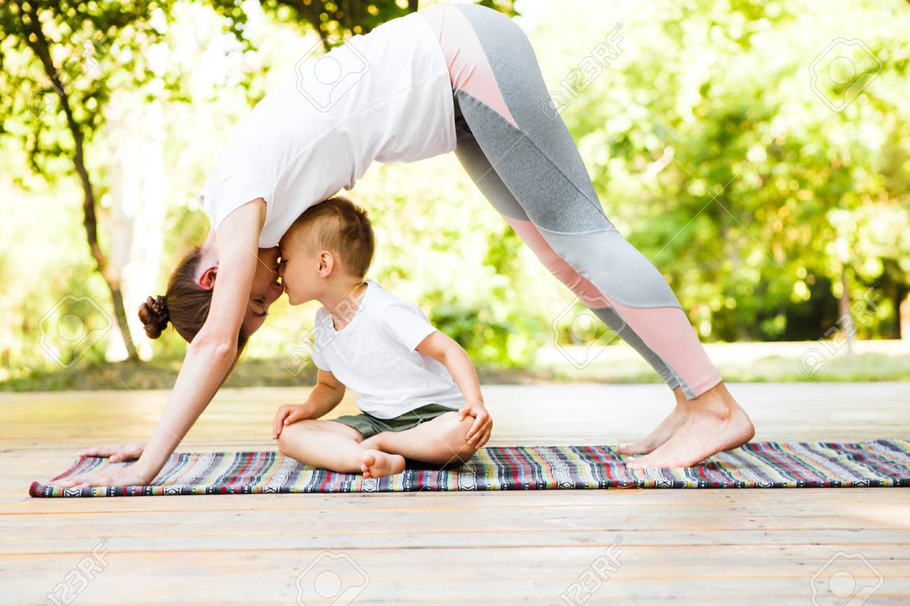 Mom And Son Are Practicing Yoga In The Park. Stock Photo, Picture ...
