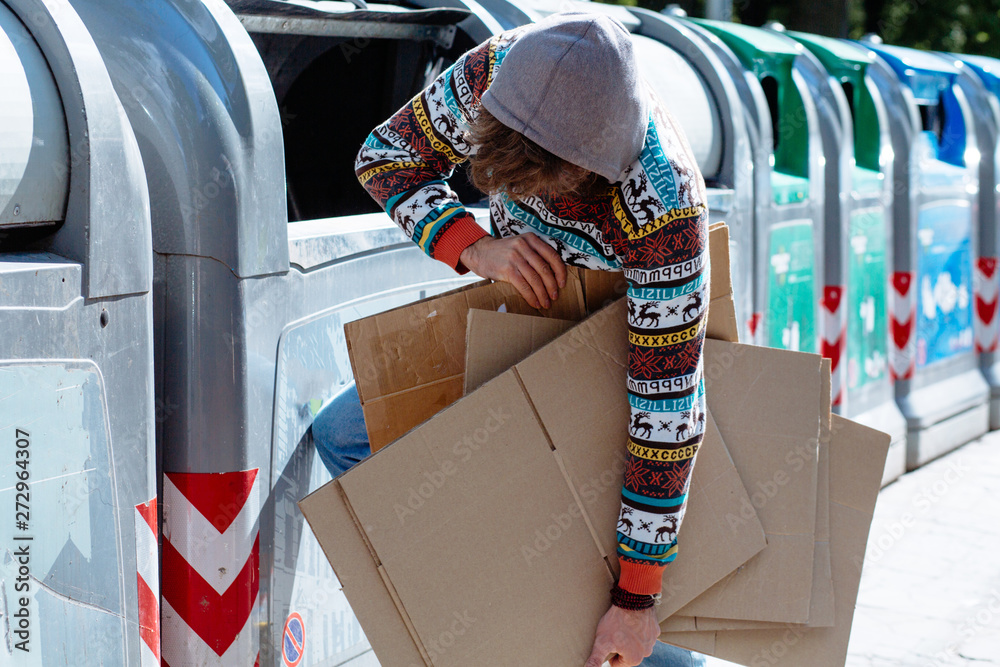 Homeless man collecting waste paper. Stylish beggar taking carton ...