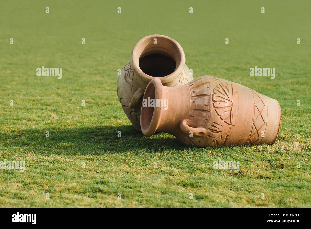 Two Clay amphora jug, old ceramic vases on green grass lawn. Sunny ...