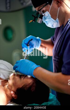 Young doctor with a magnifying glass and a syringe isolated on w ...