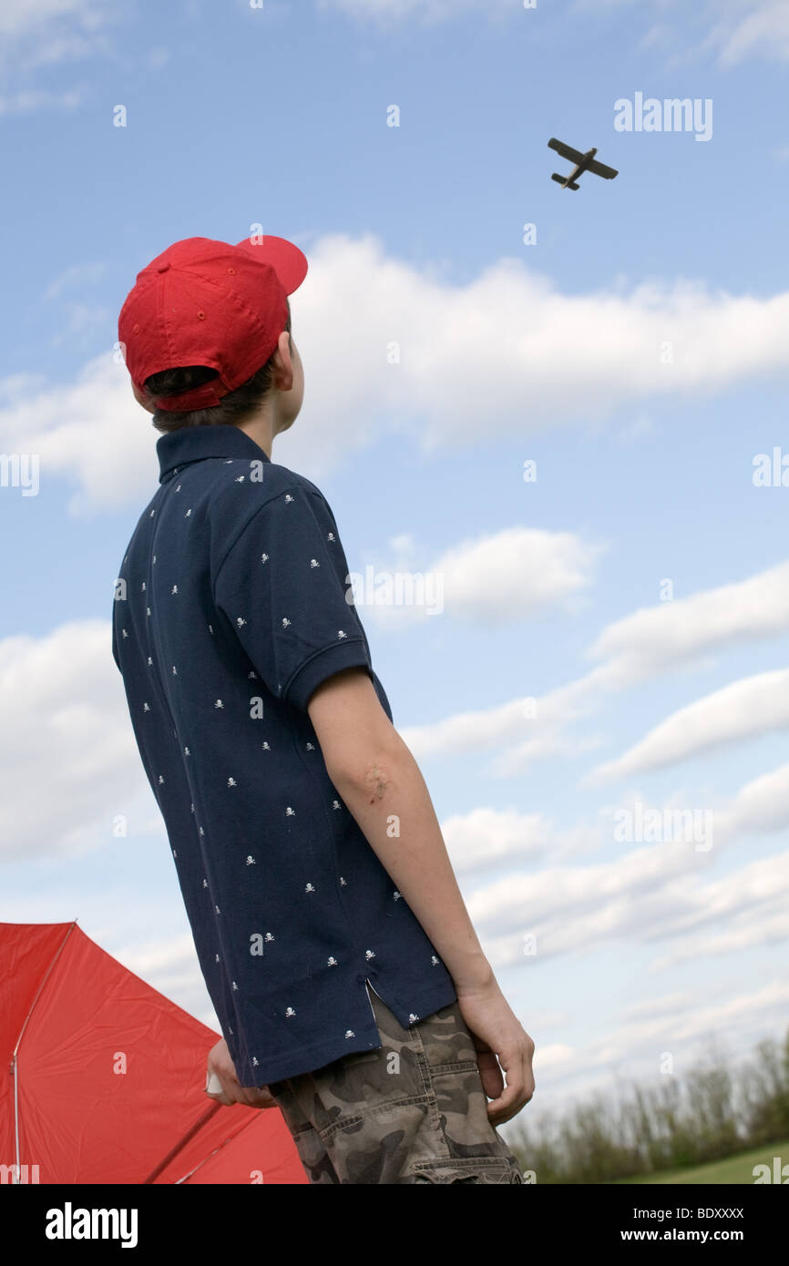 teen boy in red cap looking at plane flying in the sky Stock Photo ...