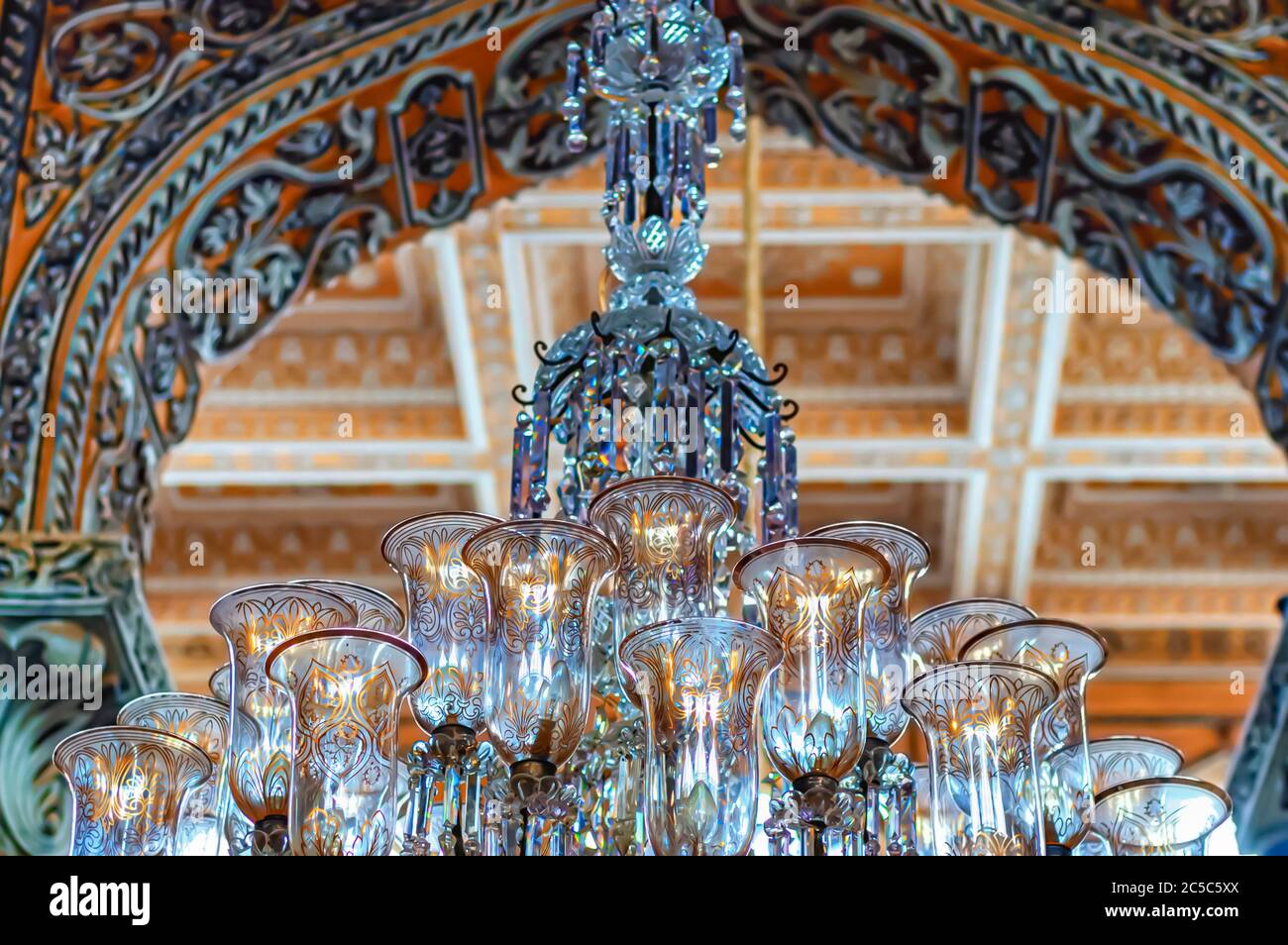 A chandelier is suspended from the ceiling adorned with ornate ...