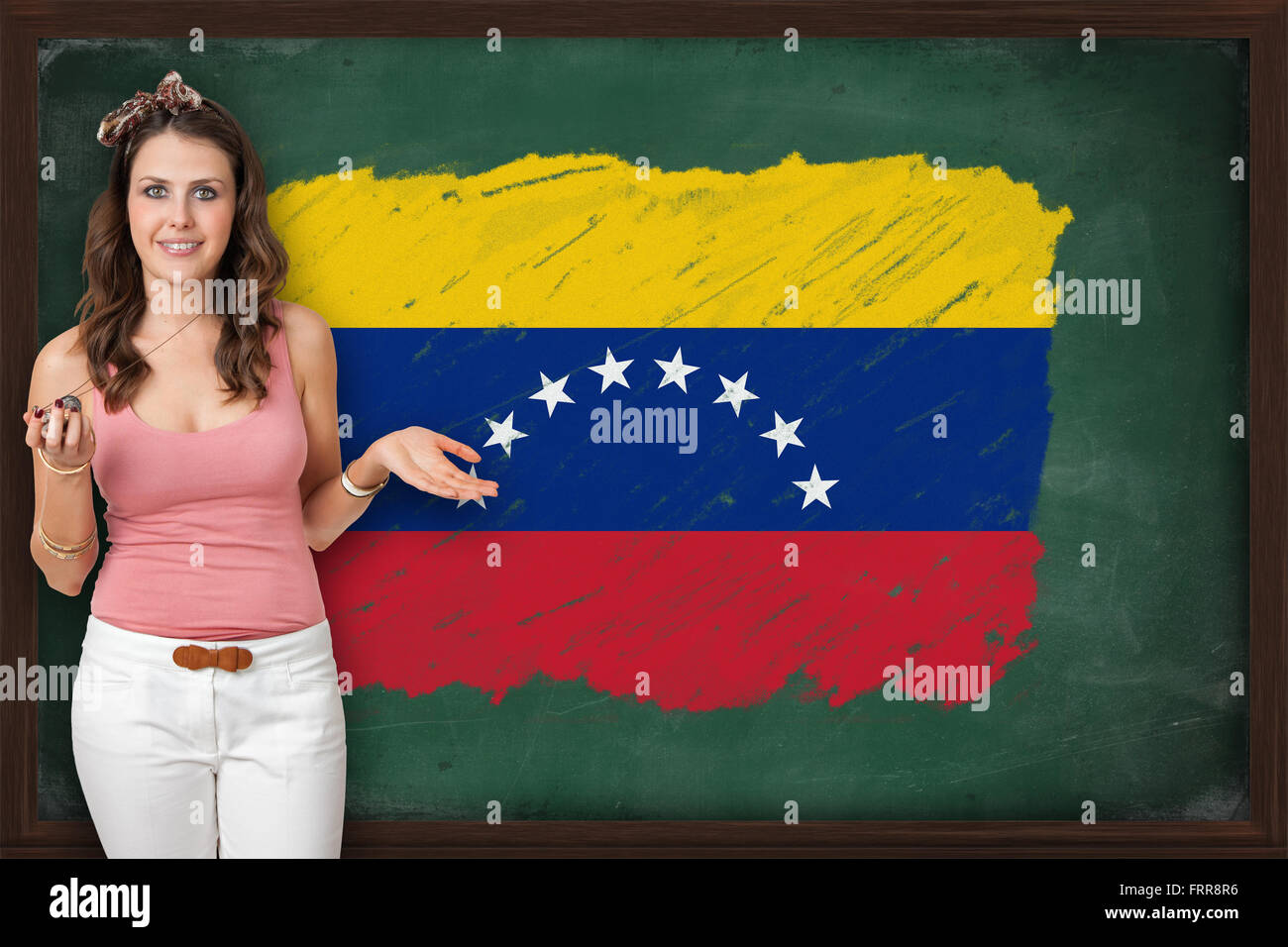 Beautiful and smiling woman showing flag of XXXXXXX on blackboard ...