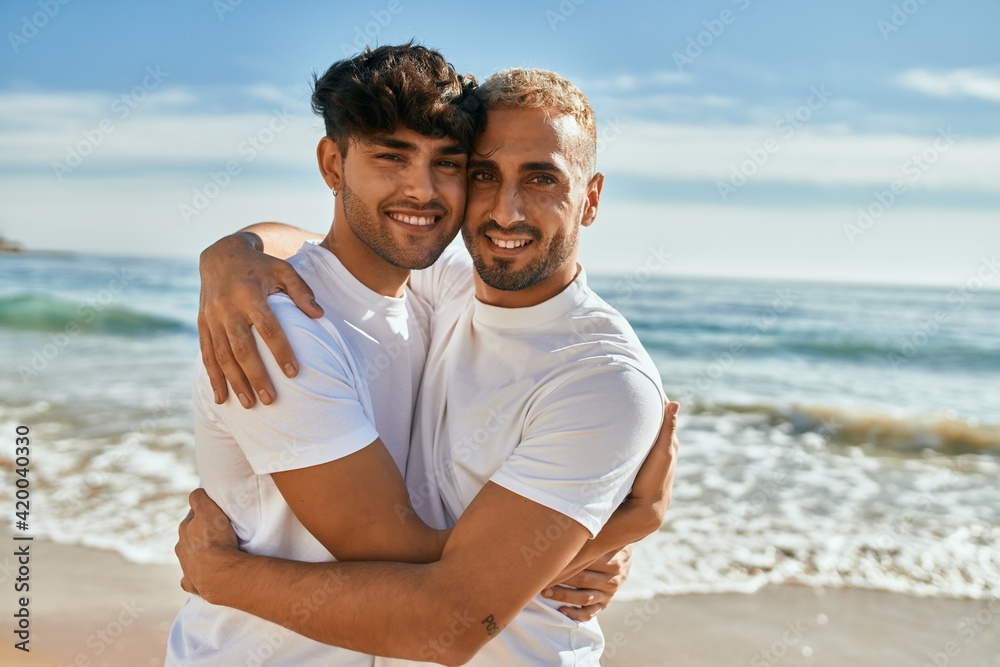 Young gay couple smiling happy hugging at the beach. Stock Photo ...