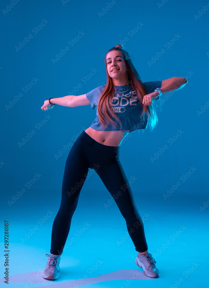 Young stylish girl dancing zumba in the Studio on a colored neon ...