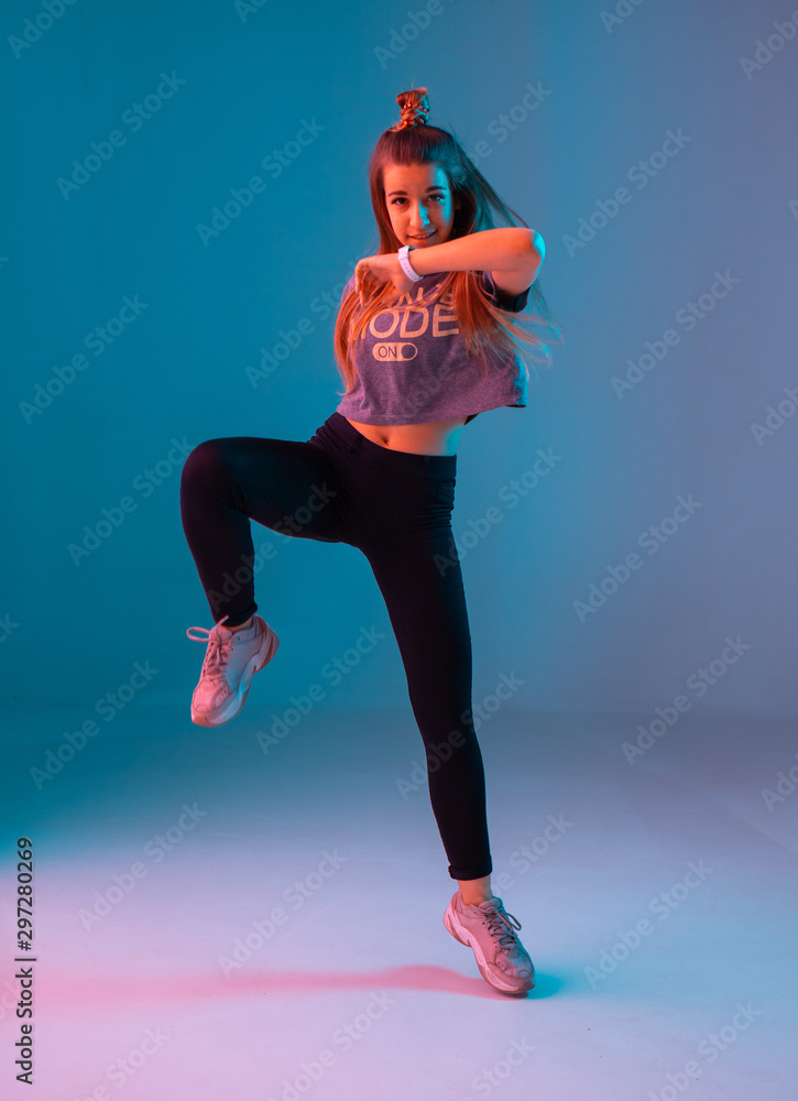 Young stylish girl dancing zumba in the Studio on a colored neon ...