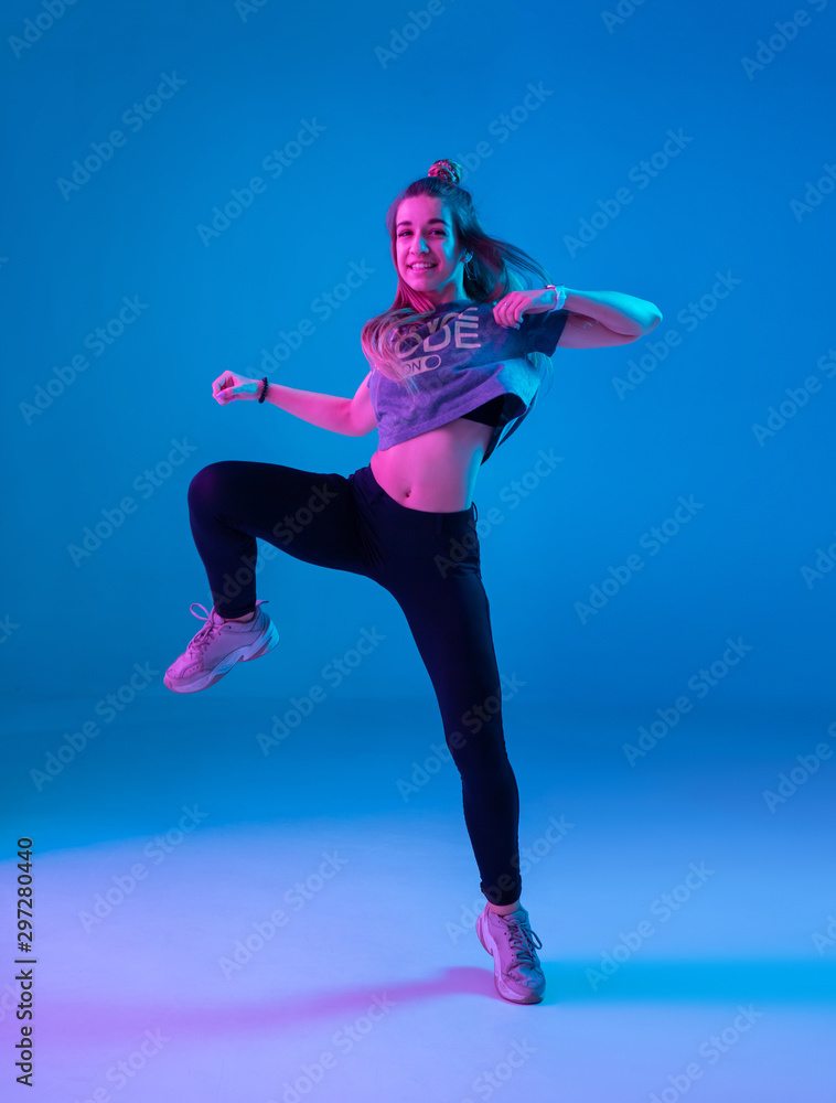 Young stylish girl dancing zumba in the Studio on a colored neon ...