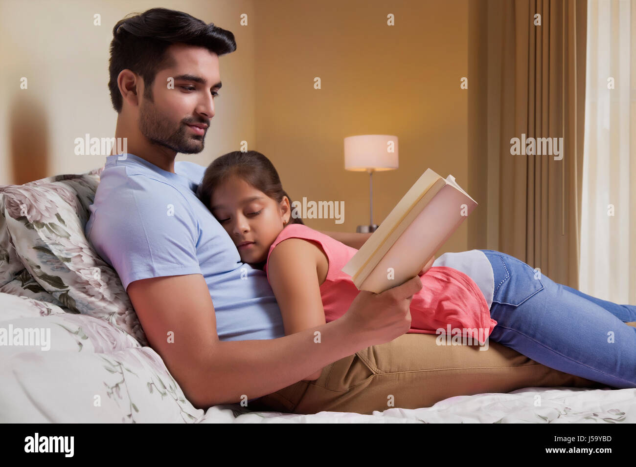 Father reading story to daughter on bed Stock Photo - Alamy