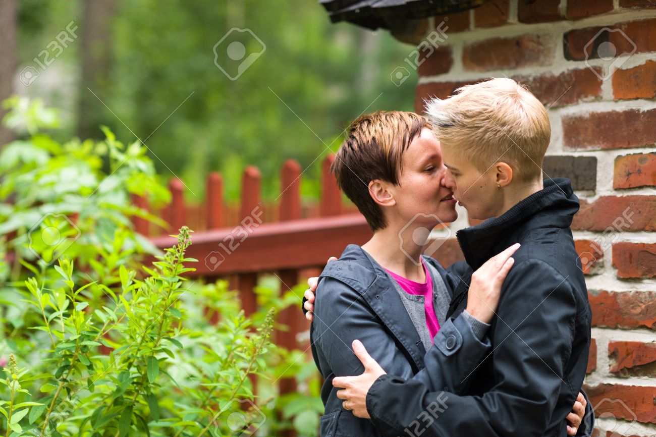 Two Girls Kissing Front Of Fence, Horizon Format Stock Photo ...